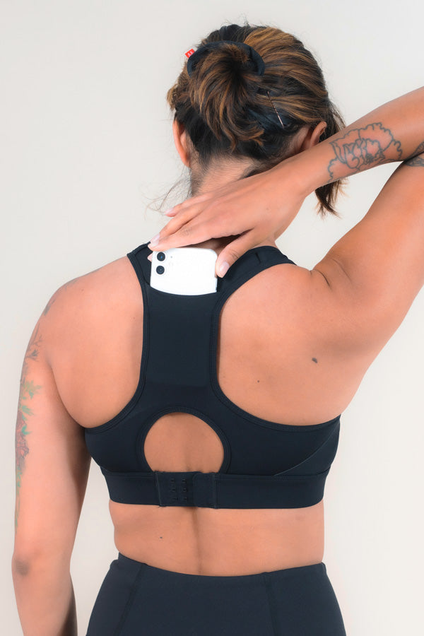 Woman placing a phone in the back pocket of her Sports Bra.