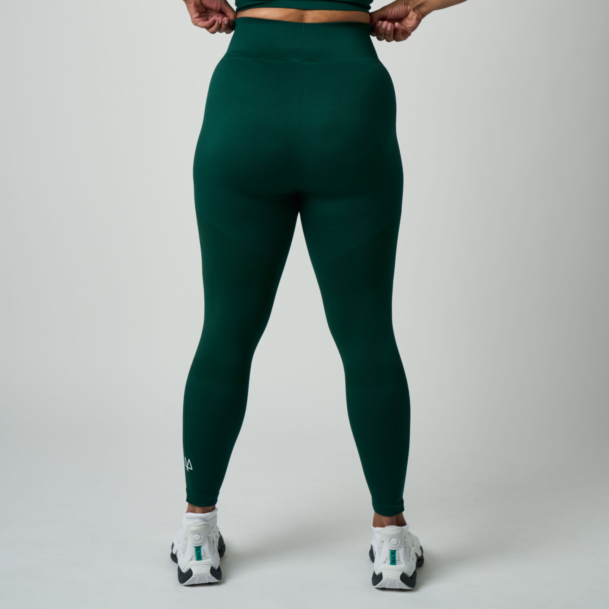 Person wearing dark green leggings on a plain background