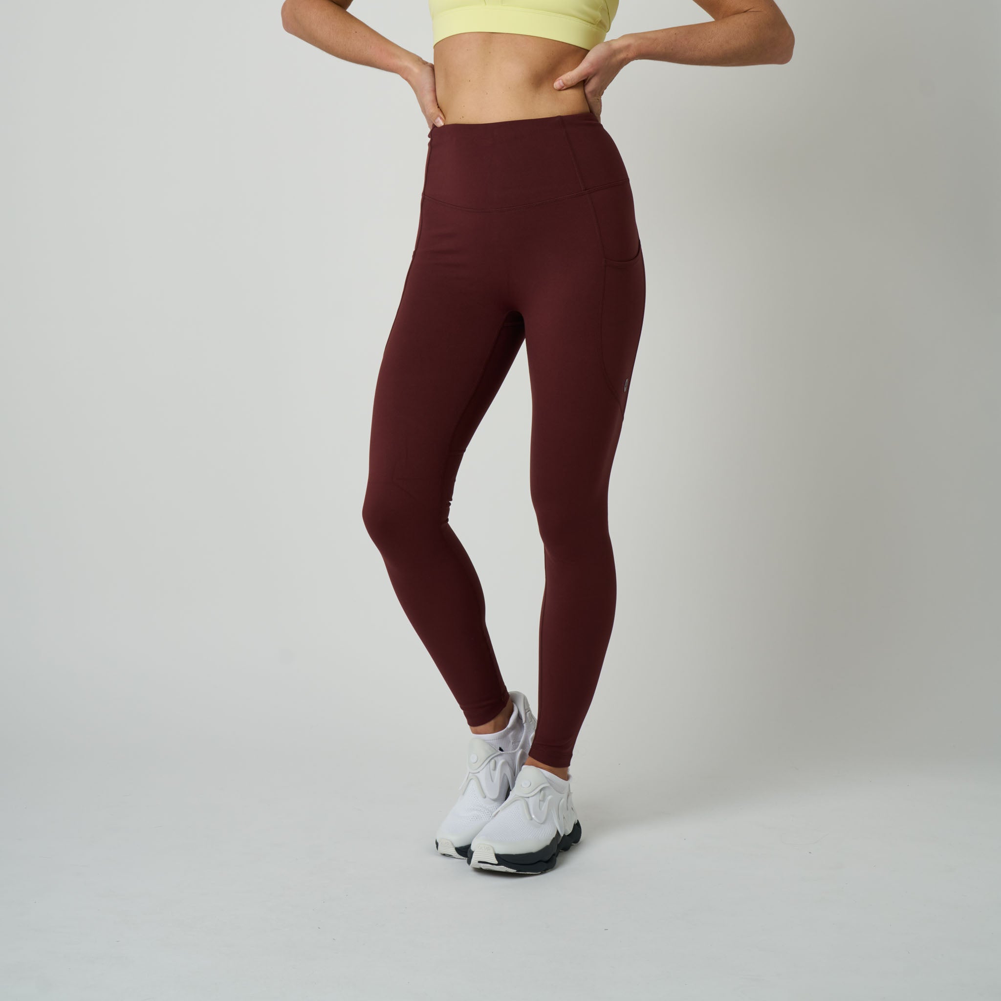 Person wearing maroon leggings and a yellow top on a plain background