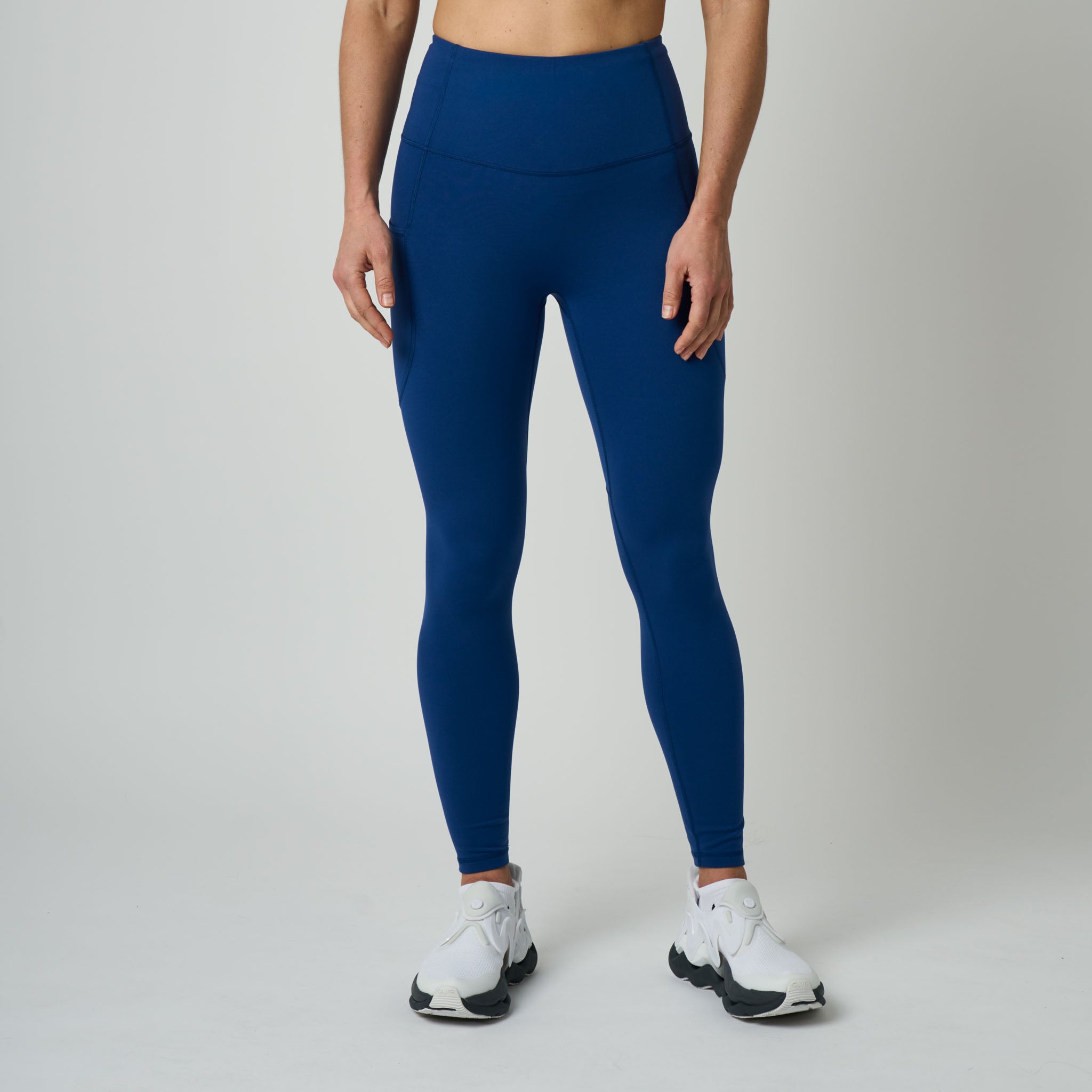 Person wearing blue leggings and white sneakers on a gray background