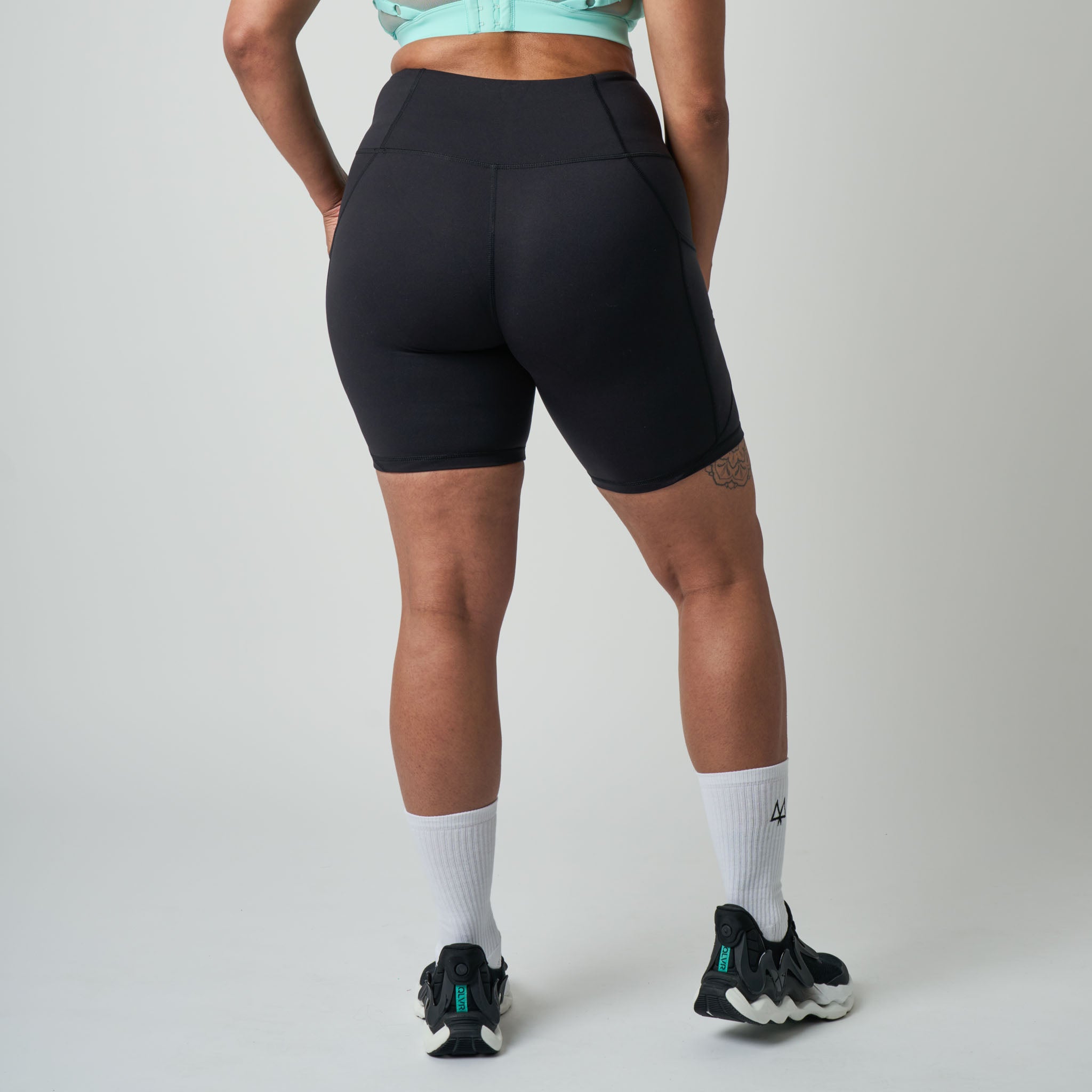 Person wearing black athletic shorts on a plain background