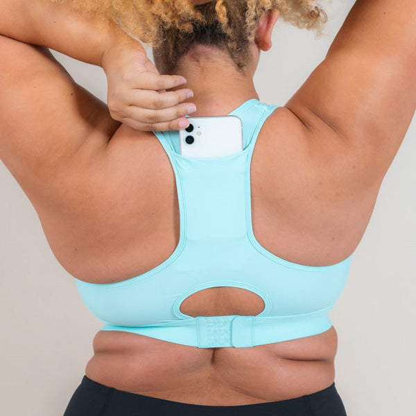Woman wearing MAAREE Empower Sports Bra in Spearmint Green colour putting phone in the back pocket