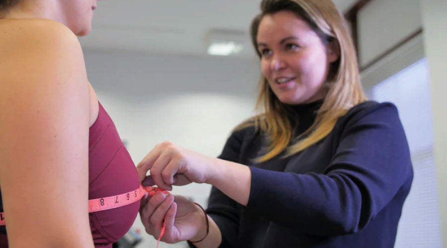 Mari, the founder of Maaree sports bras measuring a customer with a pink tape measure