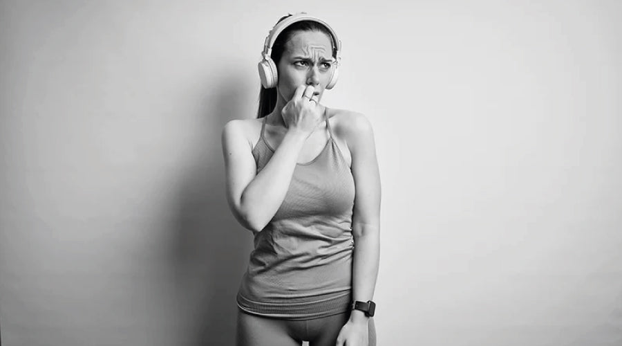Black and white photo of young lady in activewear looking worried while wearing headphones