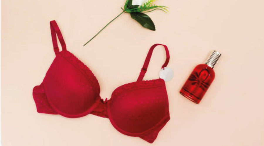Valentine's day - red bra and perfume bottle and white flower against a peach backdrop