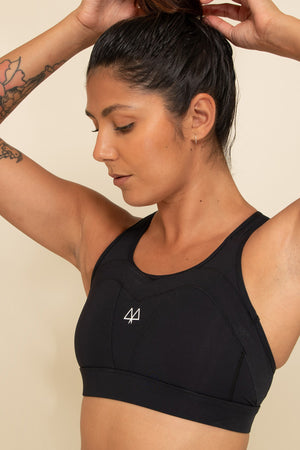 Woman wearing a supportive Black Sports Bra while playing with her hair. The MAAREE logo can be seen in White.