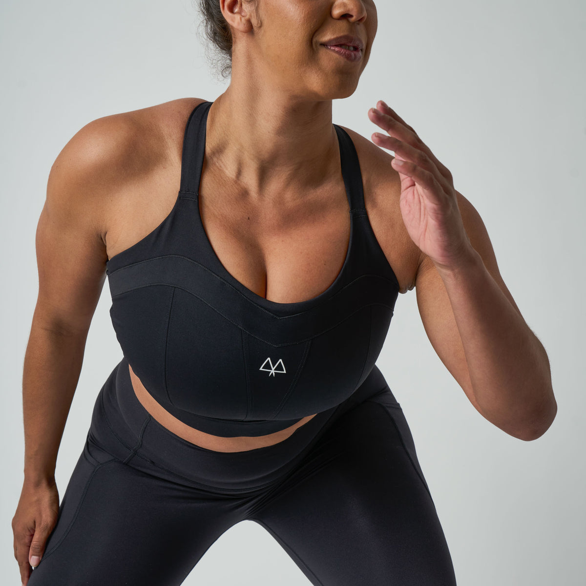 Woman wearing a black athletic outfit with a logo on a gray background