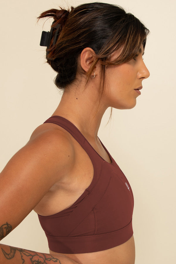 Woman in Burgundy high-support sports bra facing the side, showing the Overband Technology on the bra.