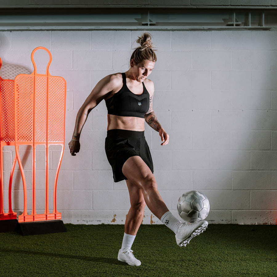 Millie_bright_kickiing_football_in_black_sports_bra_from_maaree