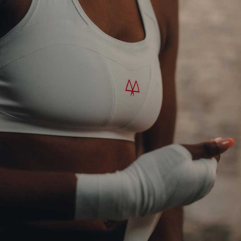 Close up view of the White medium support sports bra, focusing in on the hand ready for boxing.