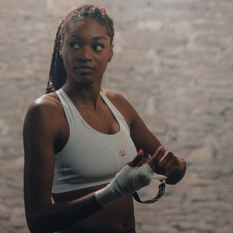 Athlete is standing in the gym in her MAAREE Medium-Impact Sports bra while wrapping her handing ready for boxing.